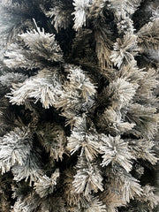 Close-up of snowy needles and flocking on slim snowy Christmas tree