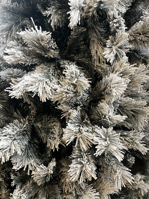 Close-up of snowy needles and flocking on slim snowy Christmas tree